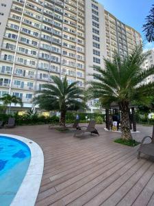 马尼拉Cozy 1 BR Apartment At South Residences Tower 2的一座棕榈树大建筑和游泳池