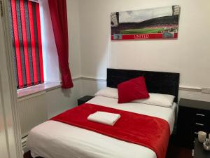 曼彻斯特Old Trafford Stadium Hotel的一间卧室配有一张带红色毯子的床