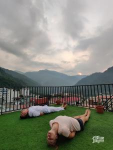 瑞诗凯诗Blue Jay Hostel Rishikesh的两个人躺在阳台上的草地上