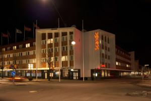 博伦厄斯堪迪克伯兰格酒店的一座建筑物,晚上在建筑物的一侧有标志