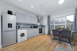 查塔姆Suites by Rehoboth - Medway Heights - Chatham Kent的厨房配有白色家电和桌椅