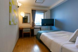 东京汤姆之家酒店 的一间卧室配有一张床和一张书桌及电视