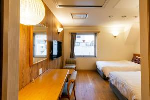东京汤姆之家酒店 的酒店客房设有两张床和一张桌子。