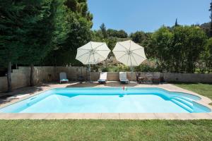 科孚镇Spitaki Pool House的一个带两把遮阳伞的庭院内的游泳池