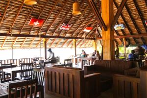 坦加拉加尼甚花园海滩小木屋的一间设有桌椅的餐厅,有坐在桌子上的人