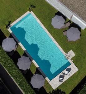 洛迦诺Smart-HOTEL MINUSIO, a Benvenuti Hotel的享有带椅子和遮阳伞的游泳池的上方景色