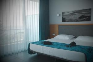 卡佩拉什Whalesbay Hotel Apartamentos的一间卧室,配有一张带两个袋子的床