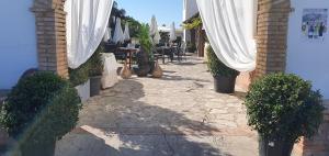 阿尔科斯-德拉弗龙特拉小精灵旅馆的庭院配有白色窗帘和桌椅