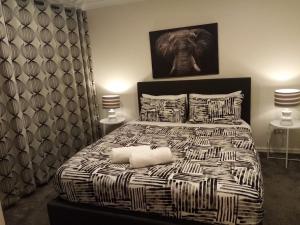 奥克兰Gulf Harbour Guest House Apartment的一间卧室配有一张带两盏灯的黑白床。