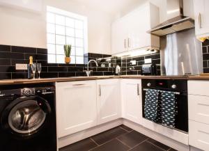埃文河畔斯特拉特福Kerns Cottage Stratford-upon-Avon的厨房配有白色橱柜、洗衣机和烘干机