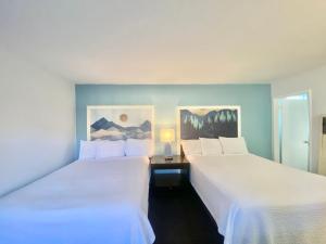 南太浩湖Bluebird Day Inn & Suites的配有白色床单的酒店客房内的两张床
