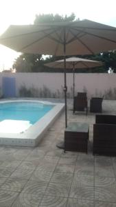 科洛里Gam Properties Guest House的游泳池旁的遮阳伞和椅子