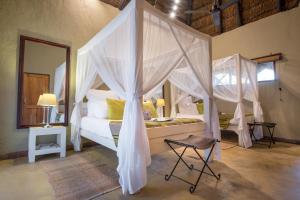 提姆巴瓦提禁猎区Kambaku Safari Lodge的一间卧室配有一张天蓬床和一把椅子