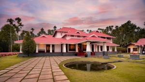 KenichiraWayanad Mace Mansion的一座有红色屋顶和池塘的房子
