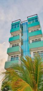 胡鲁马累Acacia Beach Hotel的一座高大的建筑,前面有一棵棕榈树
