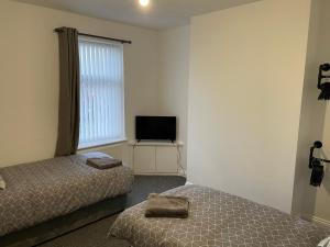BedlingtonBedlington apartment的一间卧室配有两张床和电视。