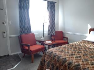 NewfaneThe Lodge at West River的酒店客房带两把椅子、一张床和窗户