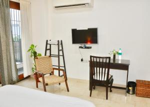 新德里Aashianaa Gracious Living的配有书桌、两把椅子和电视的房间