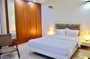 新德里Aashianaa Gracious Living的卧室配有一张白色大床和一把椅子
