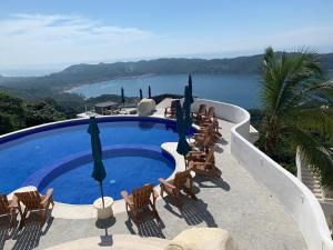 阿卡普尔科La Villa de Almudena的一个带椅子和遮阳伞的游泳池以及大海