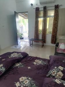 HithadhooThe Rose Garden House, Addu City, Maldives的一间卧室配有一张带紫色床单和鲜花的床