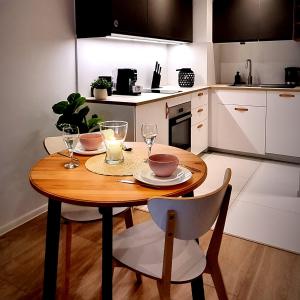 罗兹Apple Apartments - Wróblewskiego PRYWATNE MIEJSCE PARKINGOWE的一个带木桌和椅子的小厨房