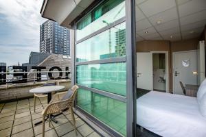 安特卫普Hotel Docklands的大楼内的阳台配有床和桌子