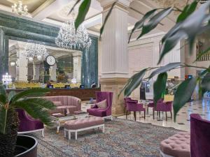 阿斯塔纳里克瑟斯酒店的大堂设有紫色椅子、桌子和时钟