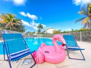 东方湾Maracuja 4, Orient Bay village, walkable beach at 100m的游泳池旁的两把椅子和一个粉红色充气火烈鸟
