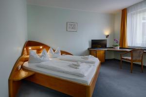 柯尼希斯武斯特豪森索菲霍夫酒店的一间卧室配有一张带白色床单的床和一张书桌。