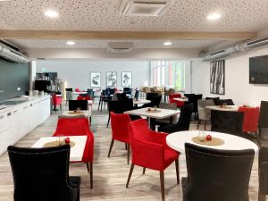 德根多夫DORMERO Hotel Deggendorf的用餐室配有桌子和红色椅子