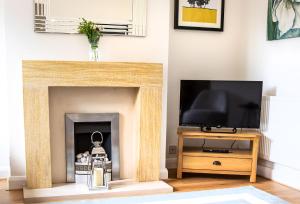 埃文河畔斯特拉特福Kerns Cottage Stratford-upon-Avon的客厅设有壁炉和电视。