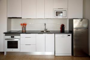 艾姆布里亚布拉瓦Apartamento Bahia III的厨房配有白色橱柜和不锈钢冰箱