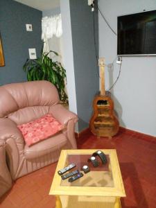 马拉圭Confort y tranquilidad al 100%的带沙发、桌子和吉他的客厅