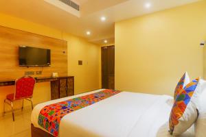 维杰亚瓦达FabHotel Surya Grand I的卧室配有一张床,墙上配有电视。