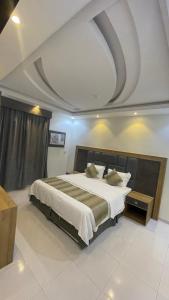 Al Qunfudhahشقق الشاطئ的一间卧室设有一张带格子天花板的大床