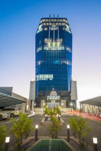 塞卡凯Tulip Plaza Hotel的停车场里高大的蓝色玻璃建筑
