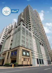 曼谷The Duchess Hotel的一座高大的建筑,前面有一个钟