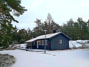 斯特伦斯塔德Hällestrand Cottage -Sillen的雪中布满树木的蓝色建筑