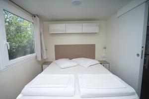 茨雷斯Mobile Homes Camping Kovačine的窗户客房内的一张白色床