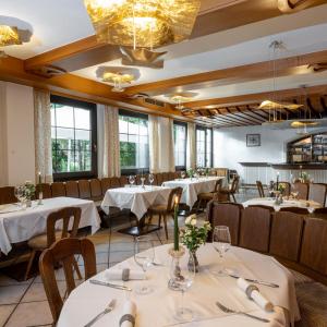 芬肯施泰因菲切特旅馆的餐厅设有白色的桌椅和窗户。