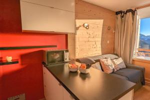 于埃Cosy studio with balcony at the heart of L'Alpe d'Huez - Welkeys的厨房以及带沙发和桌子的客厅。