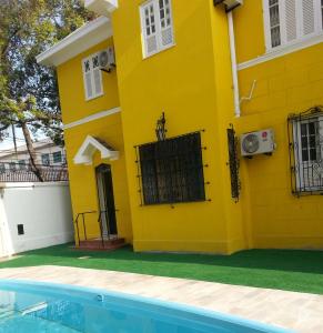 里约热内卢Arena Maracanã Hostel的一座黄色的房子,前面有一个游泳池