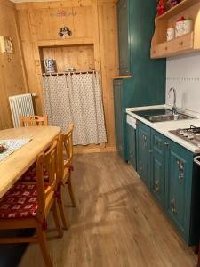 卡拉诺Casa Mia Fiemme的厨房配有绿色橱柜和木桌