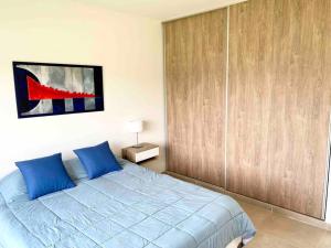 罗卡将军市Casa con pileta y parrilla en barrio privado, 2 dormitorios的一间卧室配有一张蓝色的床和一个木制衣柜