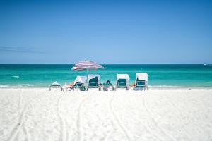霍姆斯海滩Anna Maria Beach Resort的海滩上的一组椅子和一把遮阳伞
