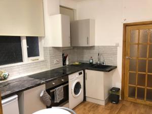 特威克纳姆Modern Apartment in Twickenham Highstreet的厨房配有白色橱柜和洗衣机。