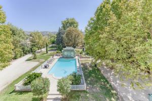 Gignac-la-NertheDOMAINE DE LA NERTHE- HOTEL PROVENCE MEDITERRANEE的花园内游泳池的顶部景色,花园内种有树木