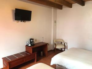 瓦曼特拉Hotel Malinalli的一间卧室配有一张床和一张桌子,墙上配有电视
