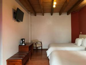 瓦曼特拉Hotel Malinalli的一间酒店客房,设有两张床和电视